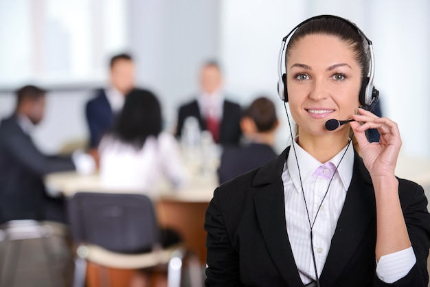 Female customer support operator with headset and smiling.