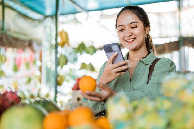 Foto cliente donna che scatta una foto ai frutti di mandarino al negozio di frutta