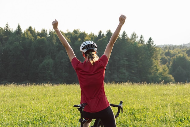 Female cycle race rider raising arms in a victory pose wide shot