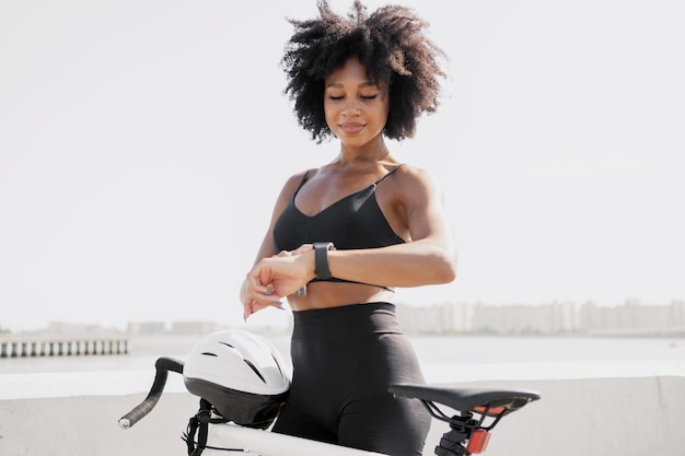 A female cyclist looks at a fitness watch measures the number of calories after a workout