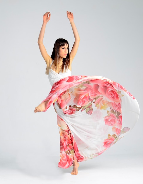 Female dancer isolated dancing with coloured dress on grey background