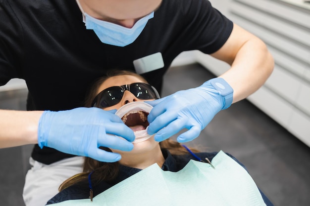 女性の歯科医は患者に快適な歯科治療のために口の拡張器を置きます
