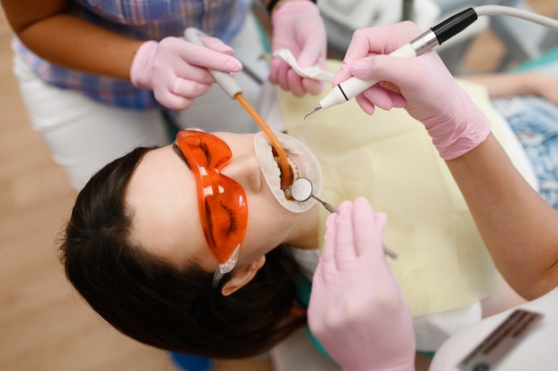 Female dentist and assistant are treats patient in clinic, stomatology