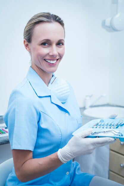 Foto il dentista femminile in blu frega tenendo il vassoio di strumenti