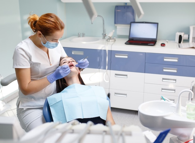 Female dentist checking patient girl teeth