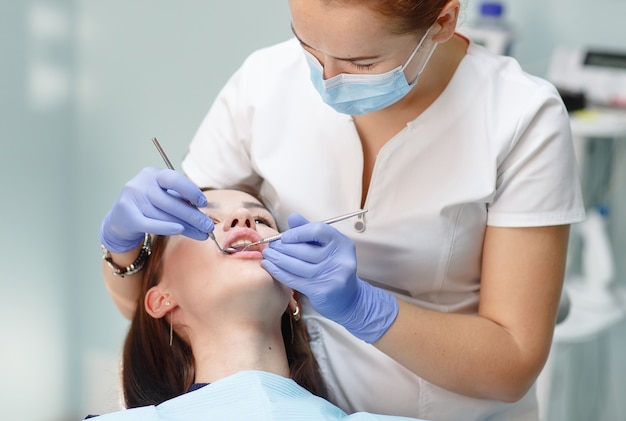 Female dentist checking patient girl teeth