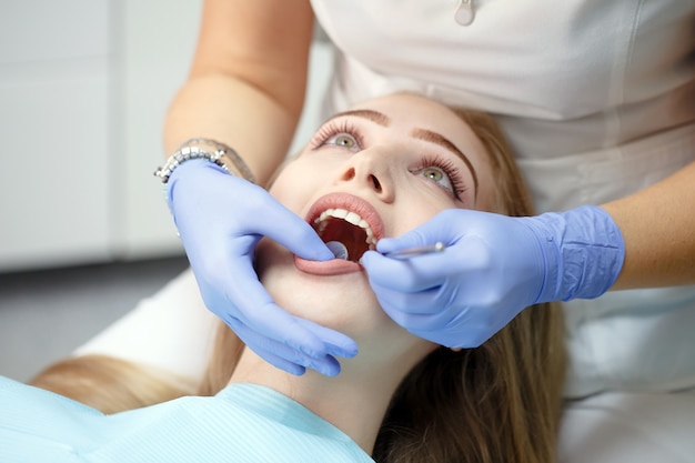 Female dentist checking patient girl teeth