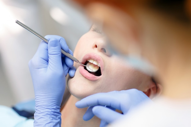 Female dentist checking patient girl teeth