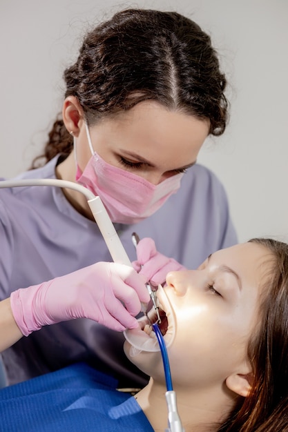 Dentista femminile che controlla i denti del paziente presso l'ufficio della clinica odontoiatrica. medicina, concetto di odontoiatria. attrezzature odontoiatriche.