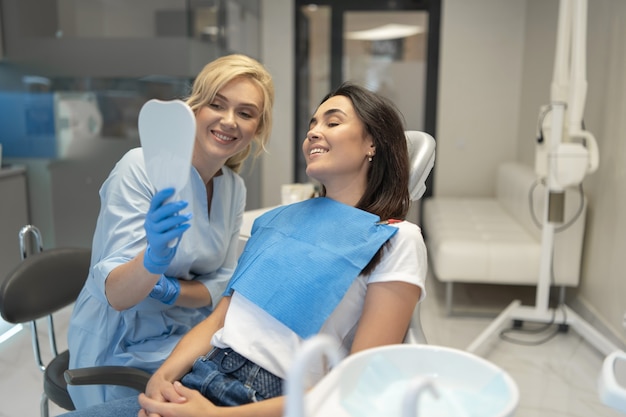 Female dentist in dental clinic providing examination and treatment of oral cavity for female patient