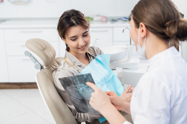 Un dentista femmina discutendo una radiografia con il suo paziente presso la clinica