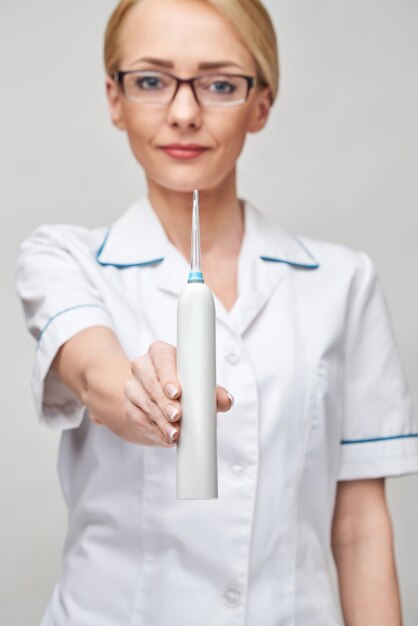 Medico dentista femminile mostra attrezzature per l'igiene irrigatore per un'attenta pulizia dei denti