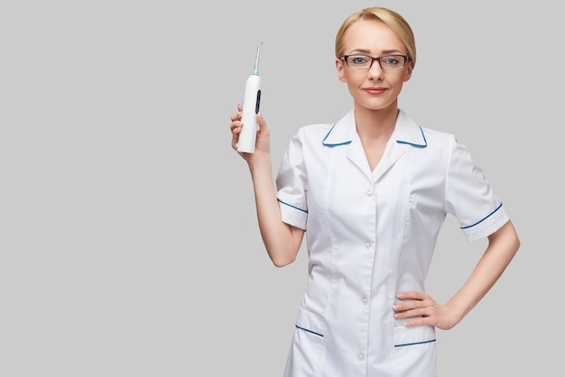 female dentist doctor shows irrigator hygiene equipment for careful teeth cleaning