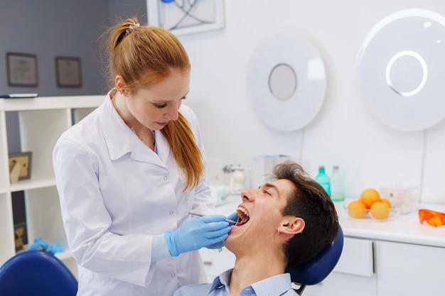 Dentista femminile che fa l'esame dei denti in un ufficio moderno