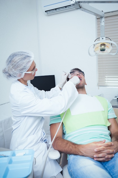 Female dentist examining mans teeth