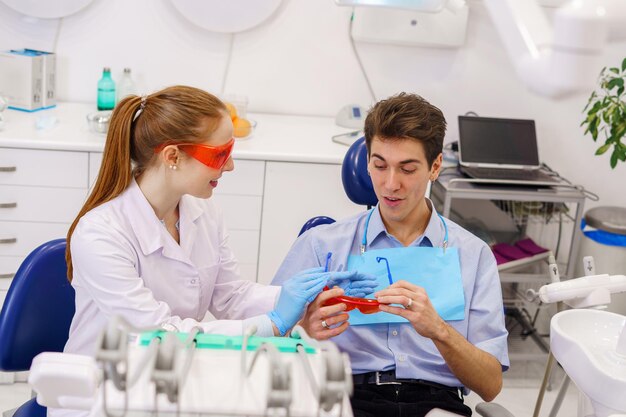 Female dentist giving goggles to male patient