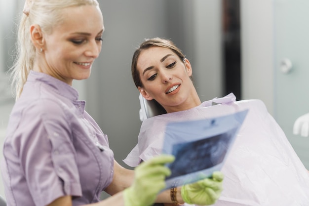 A female dentist and her young patient looking at x-ray during dental appointment.