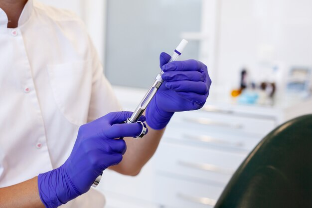 Female dentist holding syringe with anesthetic. 