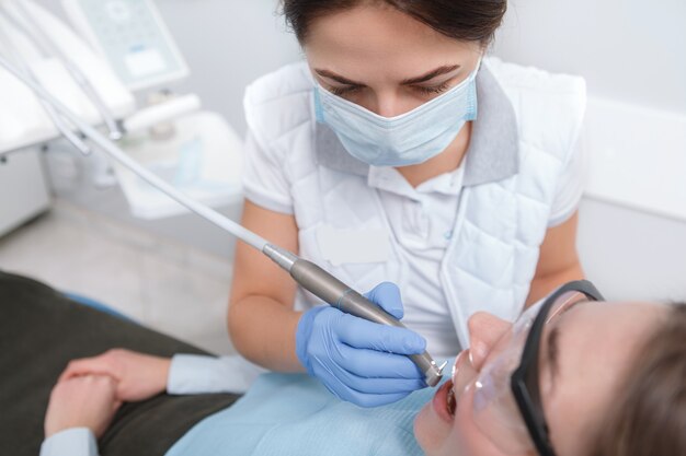 Female dentist looking focused, treating teeth of female patient