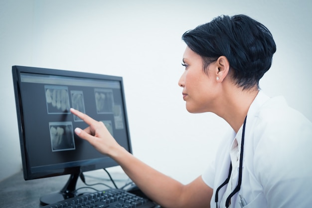 Женский стоматолог, глядя на рентген на компьютере