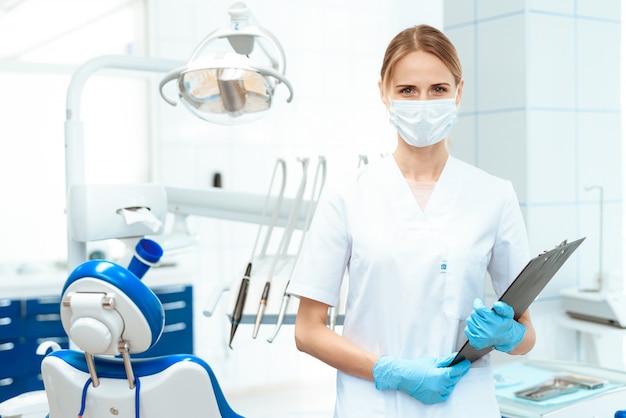 Female dentist in a medical mask posing in a dental clinic.