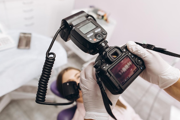 Female dentist photographs her patient's teeth in a dental chair