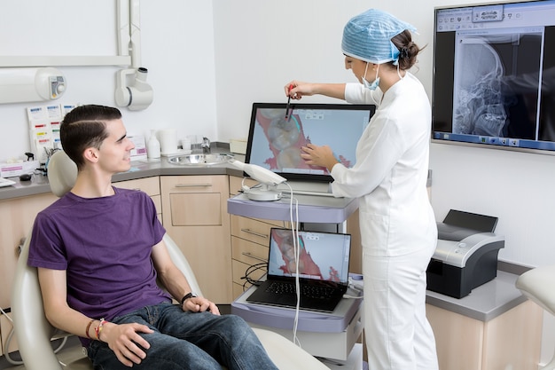 Female dentist showing tooth cavity to a patient