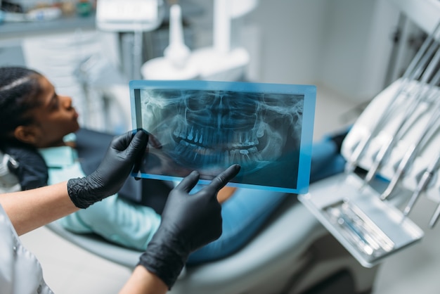 Female dentist shows problem on x-ray picture