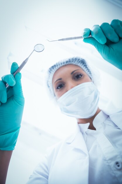 Female dentist in surgical mask holding dental tools