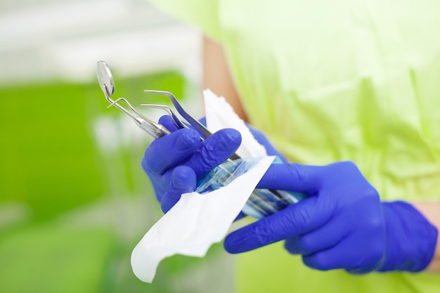 Female dentist take dental tools packed in a protective foil