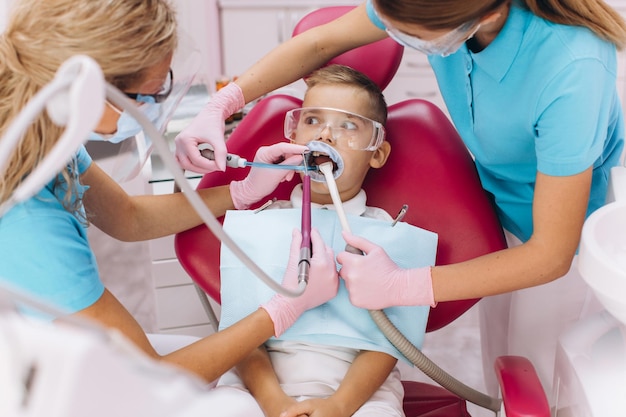 Foto il dentista femminile tratta i denti del ragazzo in clinica odontoiatrica