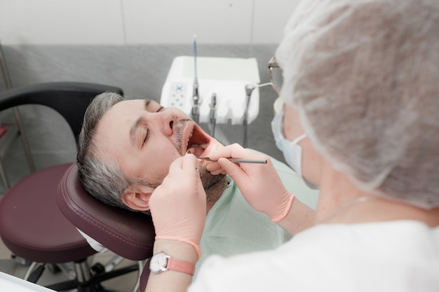 Photo a female dentist treats the teeth of a male patient in the office of a dental clinic