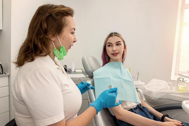Female dentist who is interviewing a patient's medical history asks for information from a female patient before treatment sitting on a chair dentistry
