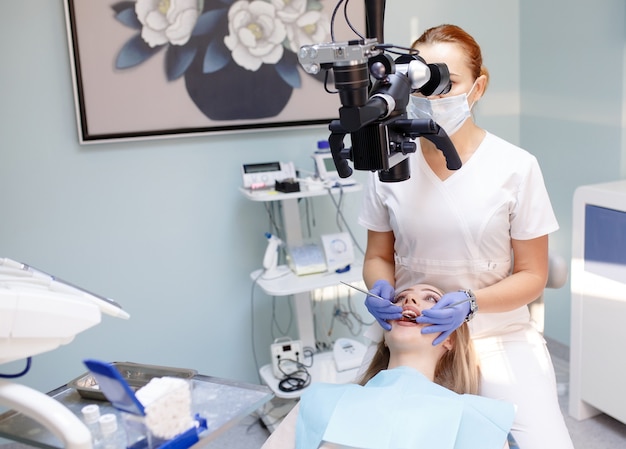 Dentista femminile con strumenti dentali - microscopio, specchio e sonda che trattano i denti dei pazienti presso l'ufficio della clinica dentale, medicina, odontoiatria e concetto di assistenza sanitaria, apparecchiature dentali