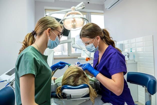 Female dentist with the help of an assistant conducts a professional examination of the patient's oral cavity