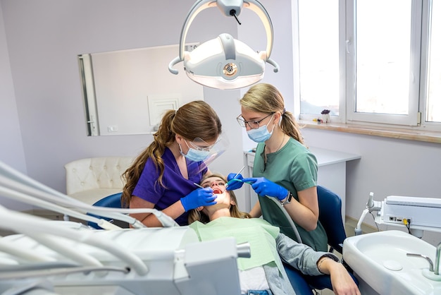 Female dentist with the help of an assistant conducts a professional examination of the patient's oral cavity