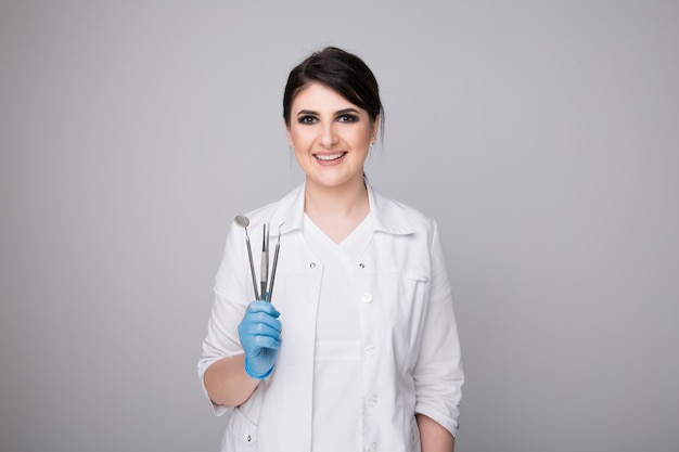 Female dentist with tools on grey background