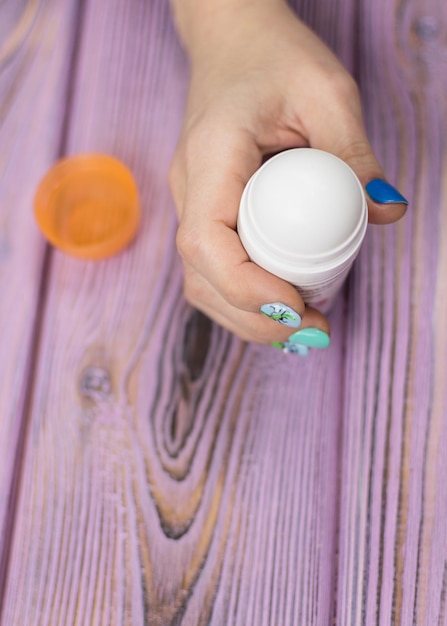 Female deodorant in hand on a wooden background