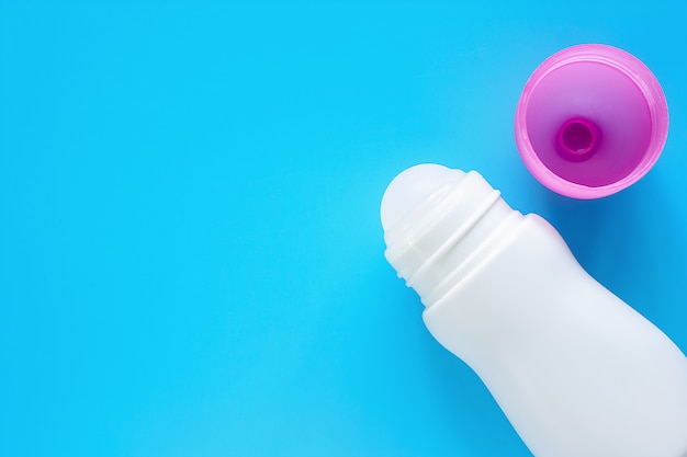 Foto deodorante femminile o rotolo sulla bottiglia con copertura rosa su fondo blu