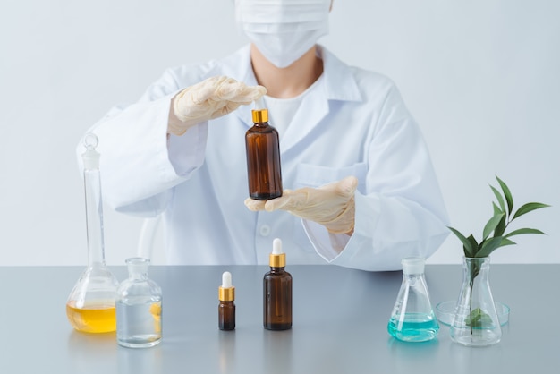 Female dermatologist holding bottle of skin care product over table, closeup