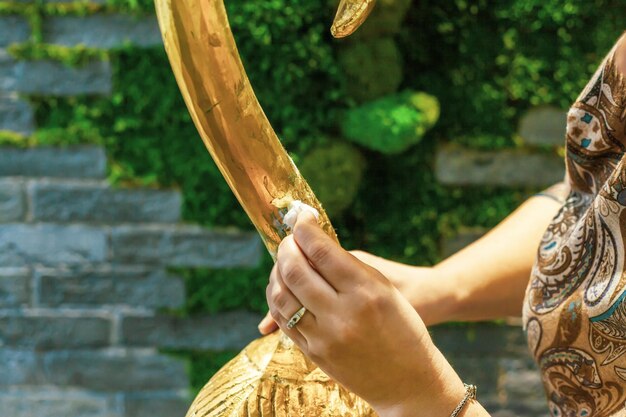 A female designer restores and covers a wooden flamingo statuette with a golden potala