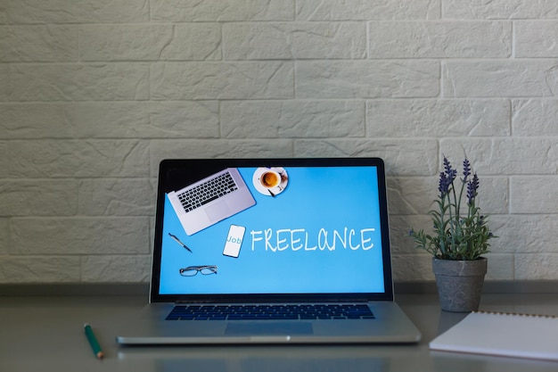 Female designer using laptop, sketching at blank notepad. Woman hand writing in notebook on wooden desk.