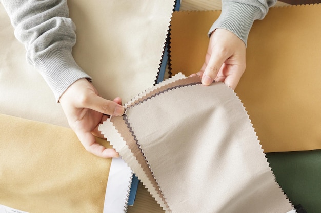 Female designer with fabric color samples choosing textile for curtains