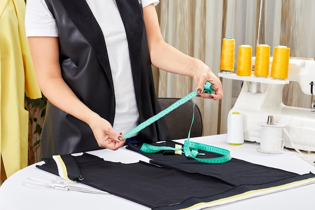 Female designer working with measure tape and sketches Fashion tailor or sewer in workshop designing new clothes collection Woman marking fabric in dressmaking salon