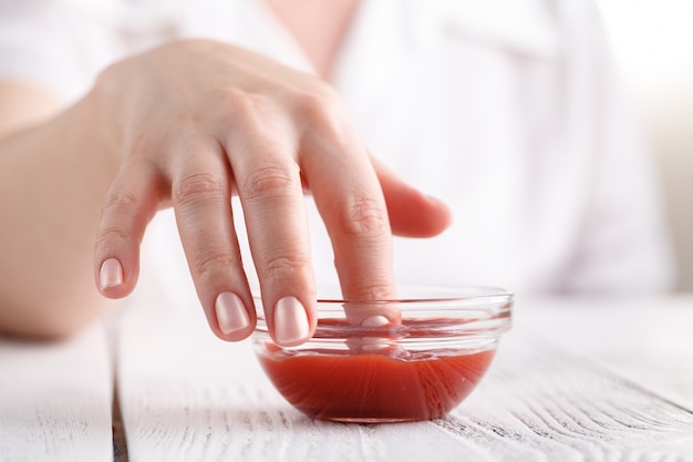 Женский окунающий палец в томатный кетчуп