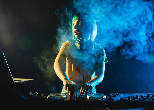 Photo female dj in club covered by colorful smoke