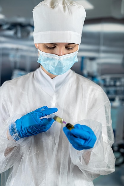 Female doctor or assistant wearing blue uniform holding syringe with medicine in surgery room