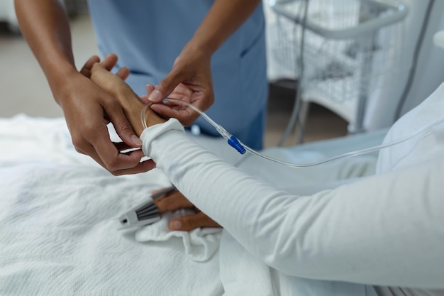 Female doctor attaching iv drip on female patient hand