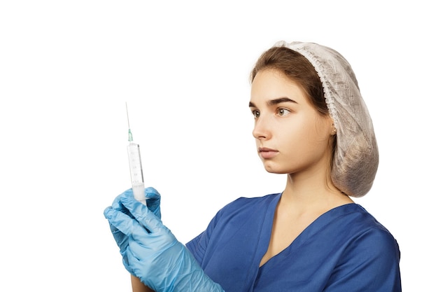 A female doctor in blue gloves and a surgical gown holds a syringe with a drug in her hands in front of her Health concept Anesthesia or vaccine for virus and disease Hospital medical care