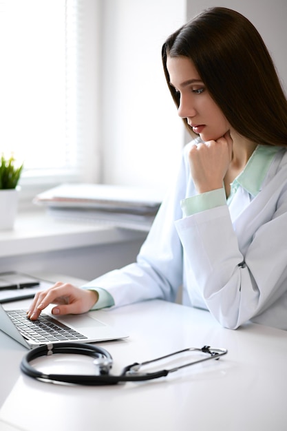 Female doctor brunette sitting at the table near the window in hospital